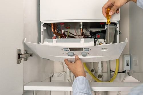 Heating technician repairing a residential boiler in Newport Beach