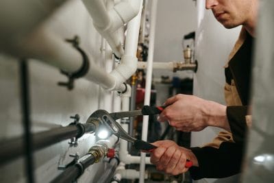 Technician inspecting commercial plumbing pipes in Newport Beach