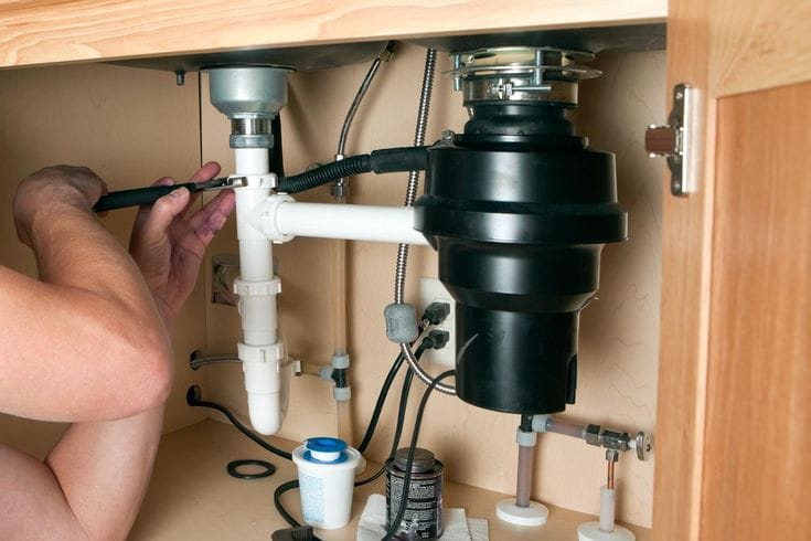 Plumber repairing a garbage disposal in Newport Beach