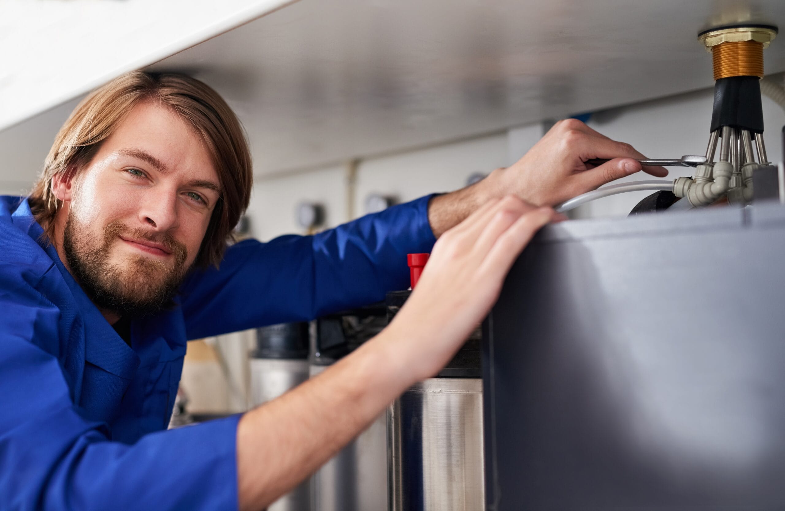 Technician servicing a residential water heater tank in Newport Beach